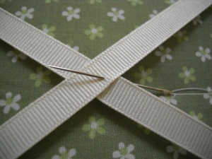 Start the needle underneath the ribbon to hide the knot. Attach the button and sew in and out through the four holes. Sew the button at least 1 or 2 times around.